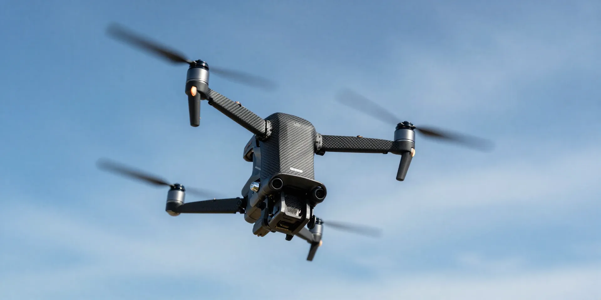 FPV drone captured mid-backflip against a bright blue sky with wispy clouds, carbon fiber frame details, cinematic lighting, high shutter speed action shot, realistic 8k --ar 16:9