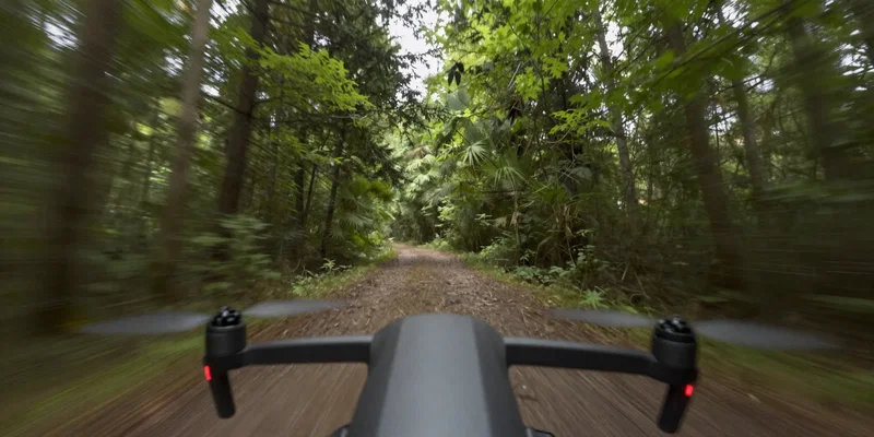 First-person view from an FPV drone diving through a dense forest path, tight tree gaps, speed lines, dynamic perspective, realistic lighting, 8k resolution --ar 16:9