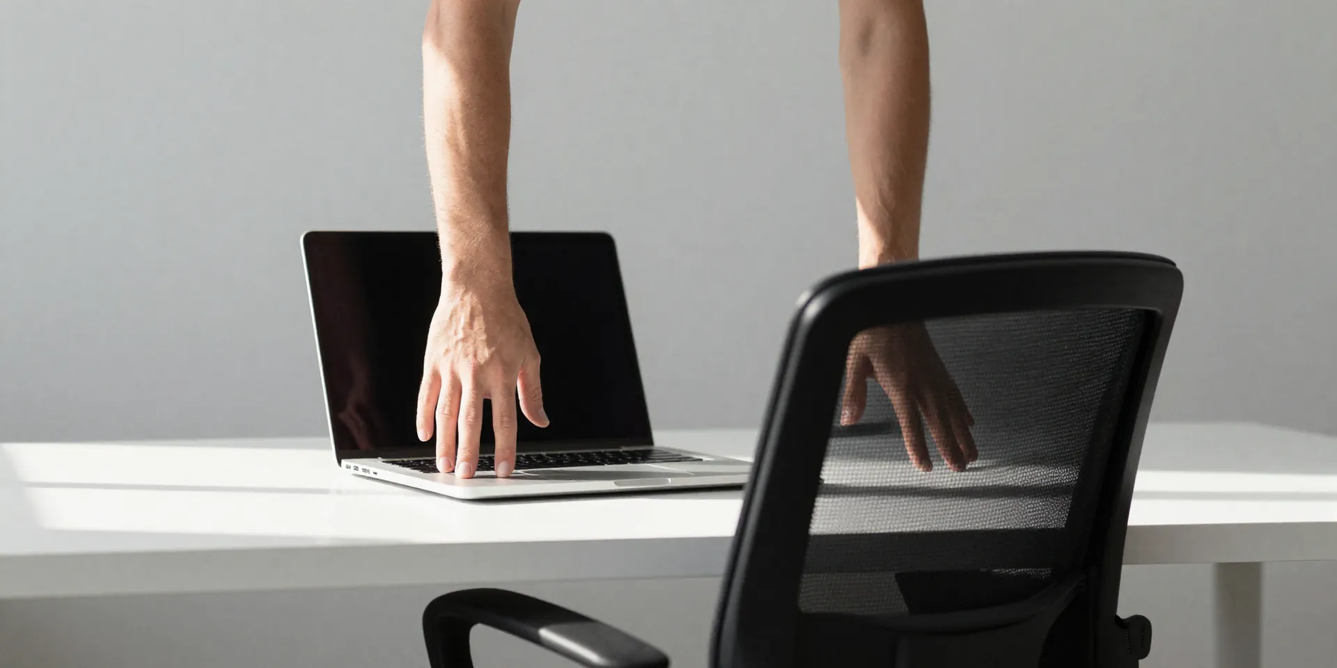 AI Image Prompt: A minimalist, clean desk set up with a laptop. A developer's hands are shown pushing up from the armrests of an ergonomic chair, mid-motion, about to stand. Sunlight streams in. Sharp focus, motivational vibe. --style raw --ar 4:5