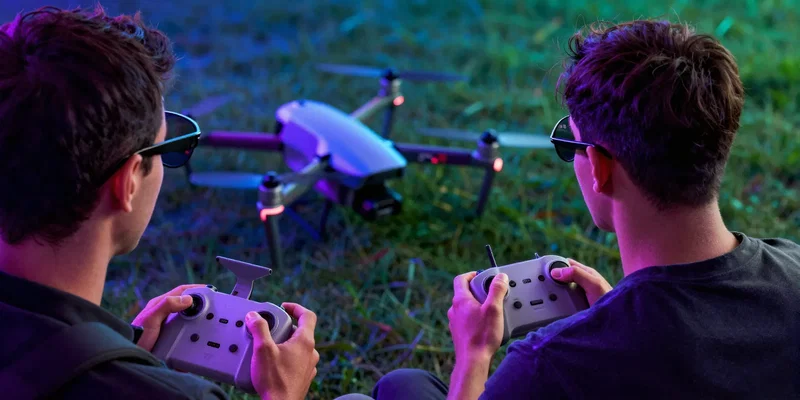 Over-the-shoulder shot of a drone pilot wearing FPV goggles, holding a remote controller, looking toward a drone on the grass, neon cyberpunk color grading, hyper-detailed --ar 16:9