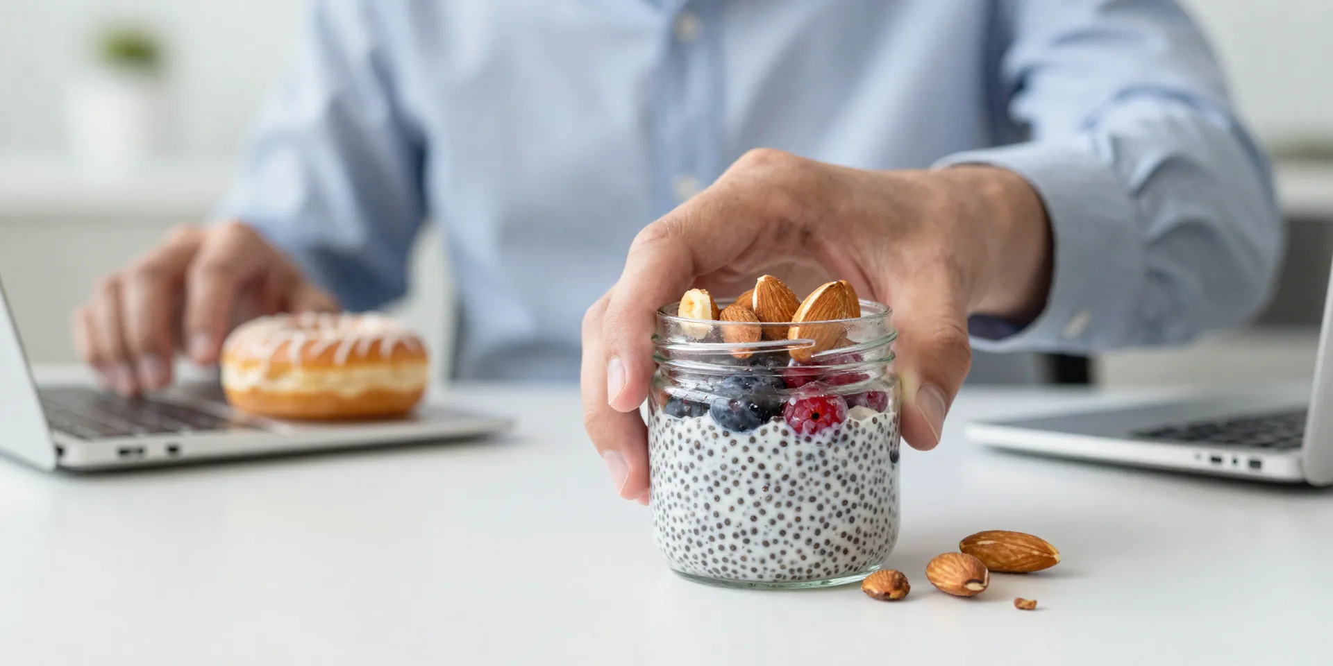 Midjourney Prompt: Hero shot from a low angle. A person's hand confidently places a delicious-looking keto snack (like a chia pudding jar with berries, or a packet of high-quality almonds) on their desk, in focus. In the blurry background, a coworker reaches for a donut. Style: Dynamic, motivational, sharp focus. --ar 16:9