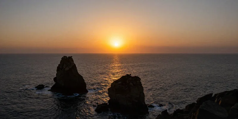 FPV drone perspective flying directly toward a massive blazing sun setting over an ocean, foreground features dark silhouetted sea stacks and jagged rocks, dramatic lighting aerial photography, cinematic color grade --ar 16:9