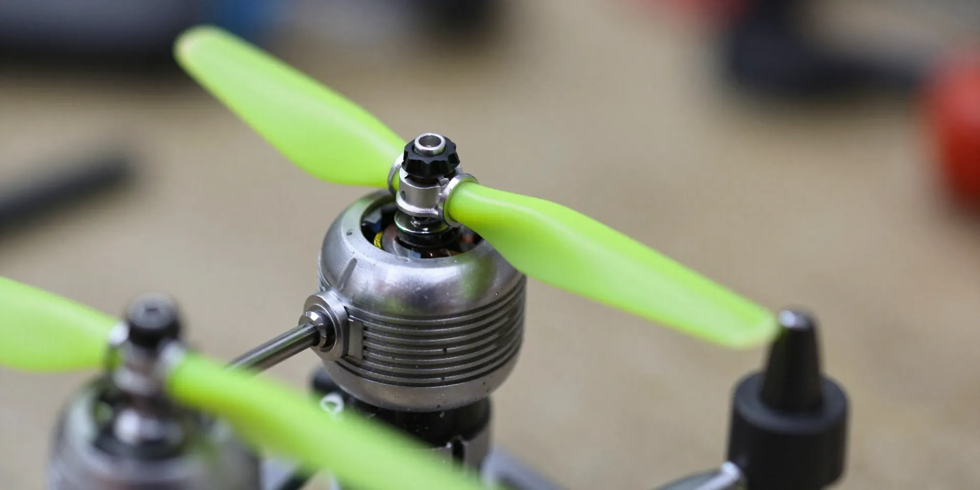 Macro photography of neon green tri-blade drone propellers being screwed onto a brushed motor, depth of field, sharp focus, workshop background --ar 16:9