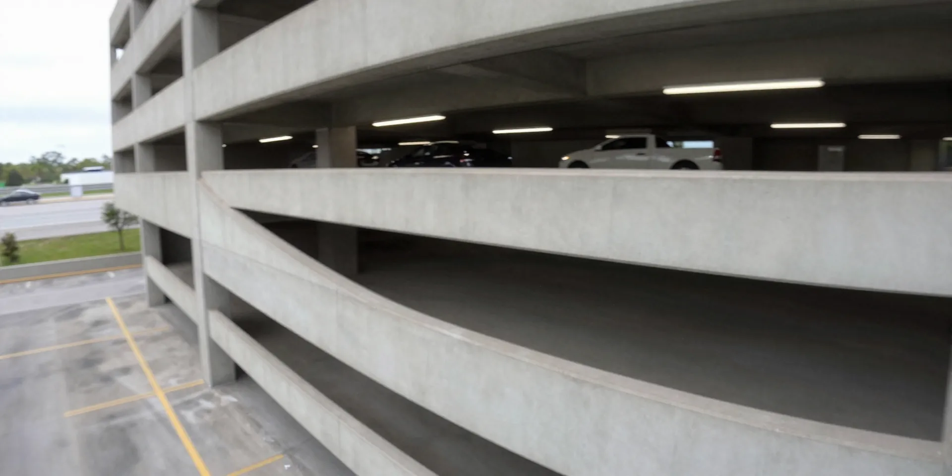First-person view from a drone diving down the side of a concrete parking garage, motion blur, gritty urban environment, dynamic action shot, GoPro style --ar 16:9