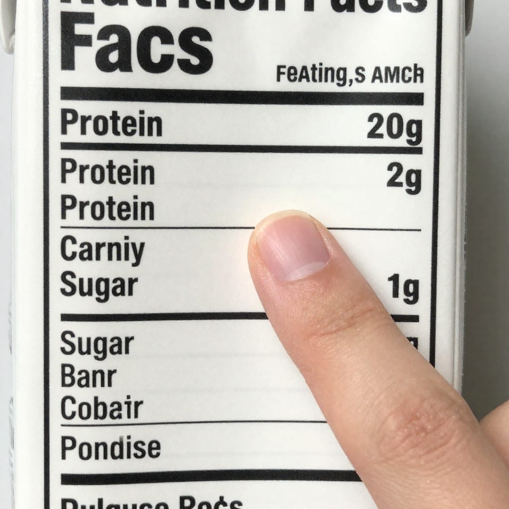 Close-up of a nutrition facts panel on a plant milk carton with a finger pointing to the protein and sugar lines