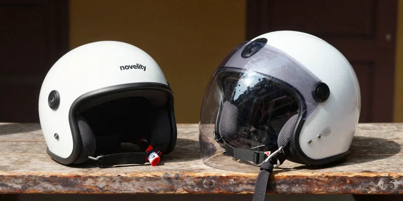 A detailed product shot of two helmets side-by-side on a rustic wooden bench in Hoi An. Left: A cheap, flimsy, plastic 'novelty' helmet. Right: A quality, full-face ECE-standard helmet with a clear visor and subtle design. Sunlight highlights the difference in build quality and materials. --ar 16:9 --v 6.0